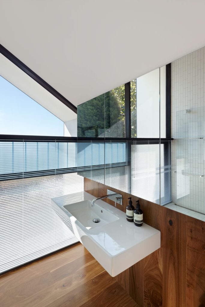 View to Master Ensuite floating vanity unit and mirror cabinet. Venetian blinds provide privacy to the bathroom from back garden. Large, glazed windows provide a well-lit bathroom space. 