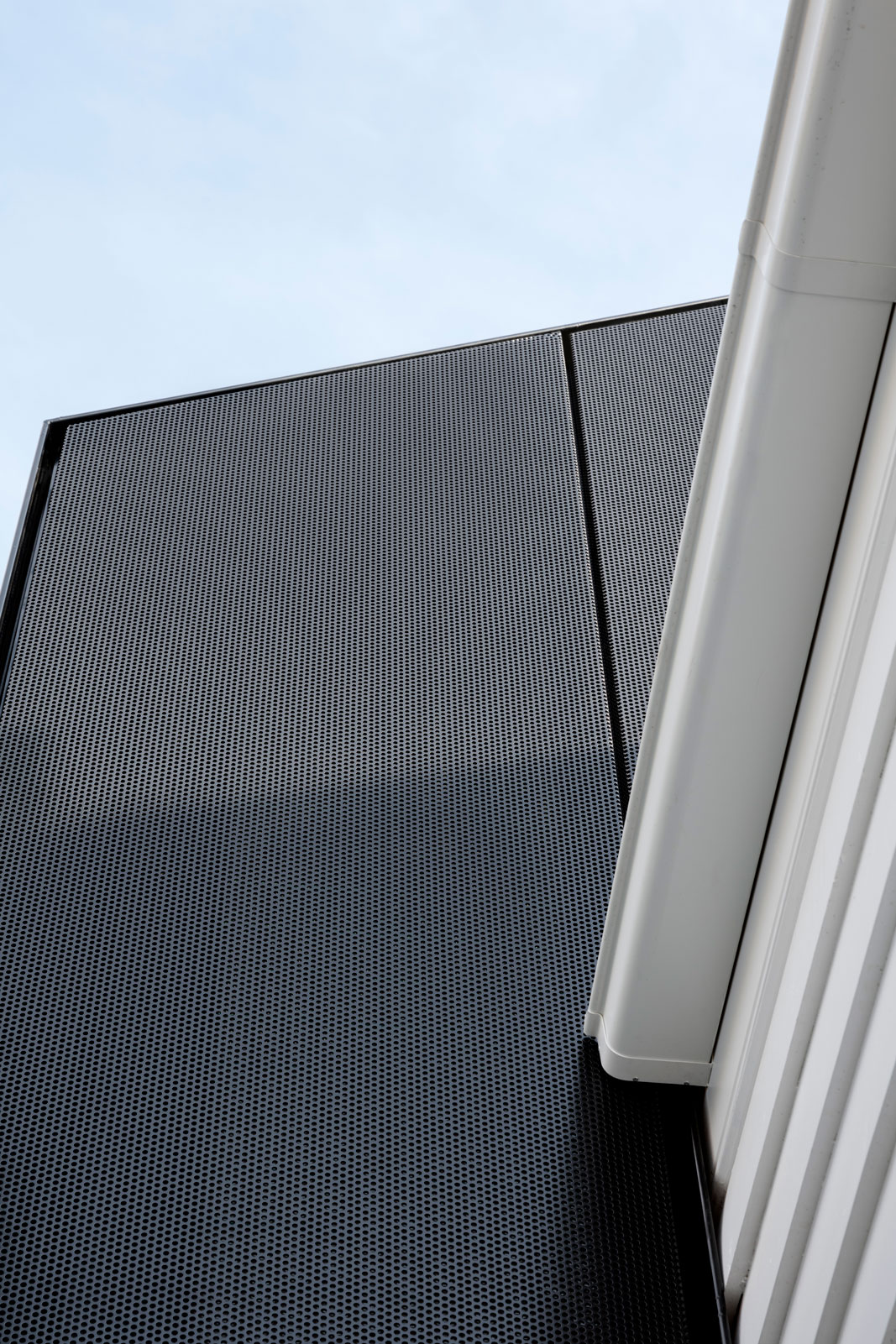 Prahran House facade Detail. The black perforated screen offers a clear differentiation between the heritage and contemporary works, creating a contrast against the white heritage weatherboard facade.