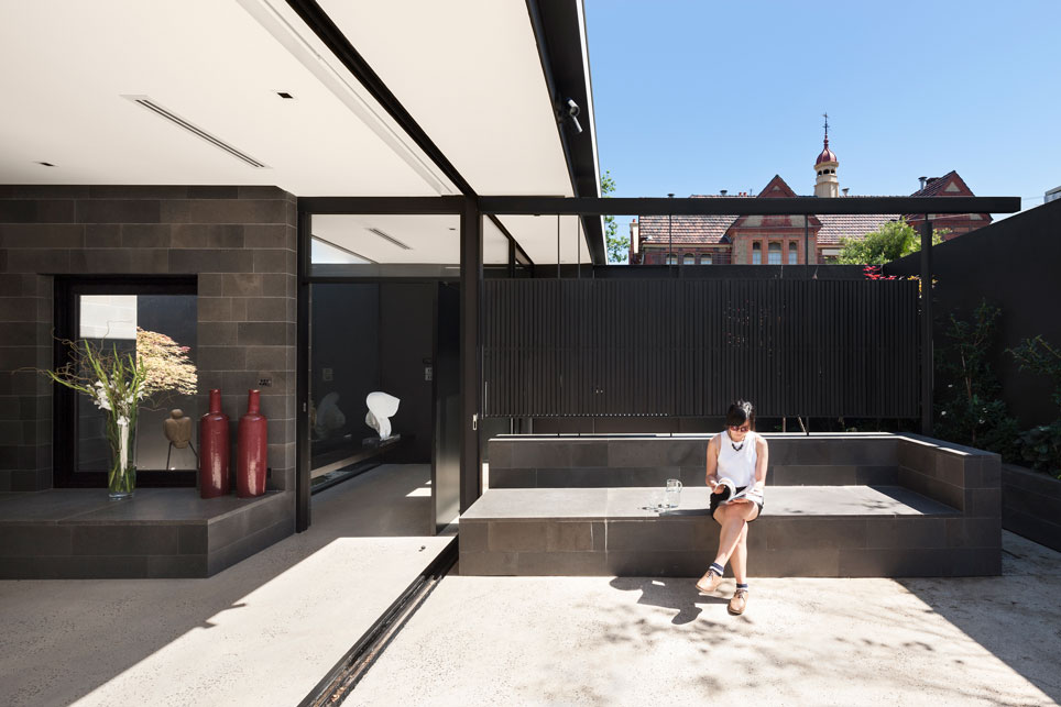 Toorak House Living Room & Internal Courtyard. Full height windows divide the living room and internal courtyard. The blue stone mass becomes an external seating and screening.